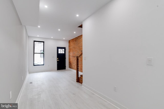 entrance foyer with baseboards, brick wall, light wood-style flooring, and recessed lighting