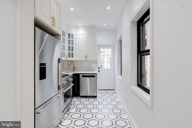 kitchen with stainless steel appliances, light countertops, white cabinetry, and glass insert cabinets