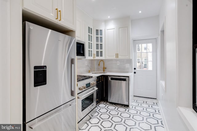 kitchen featuring light countertops, appliances with stainless steel finishes, glass insert cabinets, white cabinetry, and a sink