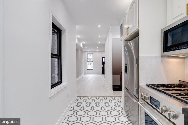 kitchen with tasteful backsplash, recessed lighting, appliances with stainless steel finishes, white cabinets, and baseboards