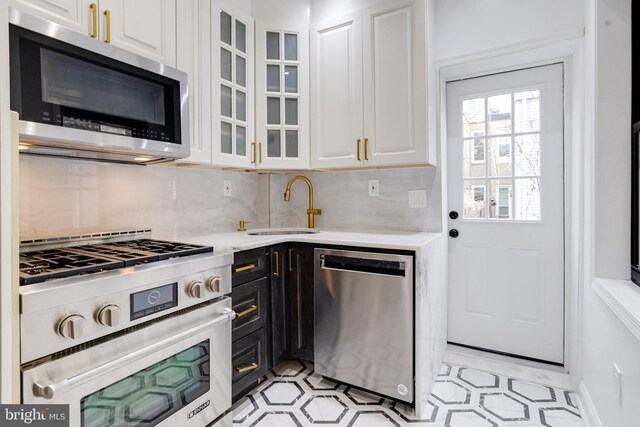 kitchen featuring stainless steel appliances, light countertops, a sink, and white cabinetry