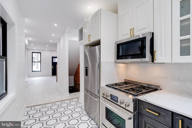 kitchen with tasteful backsplash, light countertops, appliances with stainless steel finishes, glass insert cabinets, and white cabinets