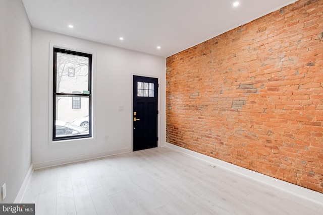 foyer entrance with brick wall, recessed lighting, light wood-style flooring, and baseboards