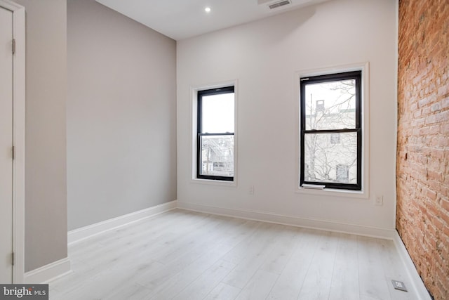 spare room with baseboards, light wood finished floors, and a healthy amount of sunlight