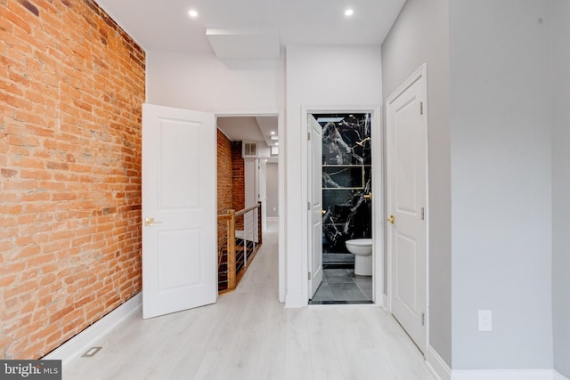 hallway with light wood-style floors, recessed lighting, and brick wall