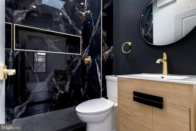 bathroom with a marble finish shower, vanity, and toilet