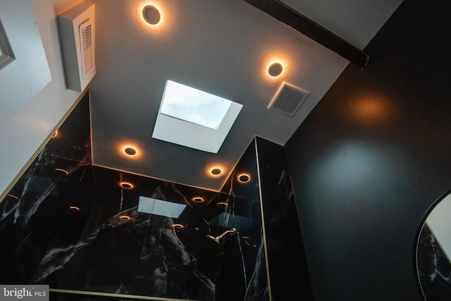 details with a skylight, a marble finish shower, and visible vents