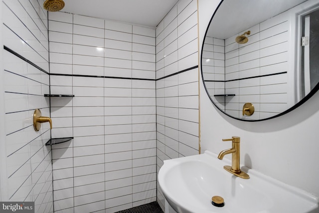 full bath with tiled shower, a sink, and tile walls