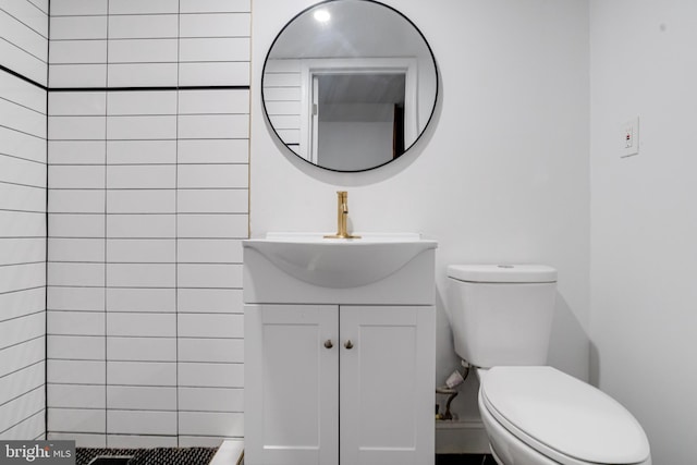 bathroom with tiled shower, vanity, and toilet