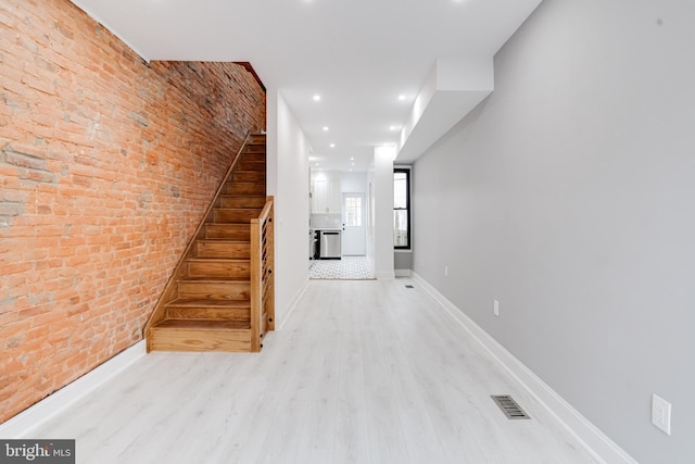 stairs with recessed lighting, visible vents, brick wall, wood finished floors, and baseboards