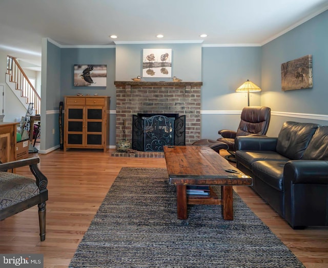 living room featuring stairs, a brick fireplace, wood finished floors, and crown molding