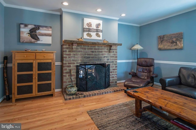 living area featuring baseboards, wood finished floors, crown molding, a brick fireplace, and recessed lighting