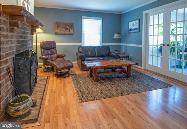 living area with baseboards, ornamental molding, wood finished floors, french doors, and a brick fireplace