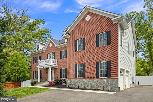 7911 Fort Hunt Rd, Alexandria, VA 22308 - colonial home featuring stone siding, an attached garage, a balcony, and driveway