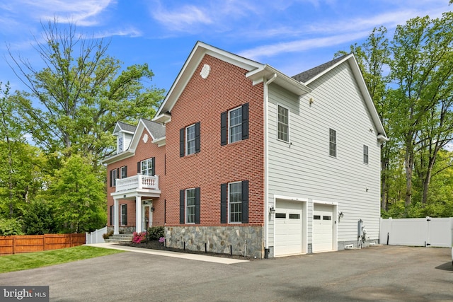7911 Fort Hunt Rd, Alexandria, VA 22308 - view of side of home featuring a balcony, asphalt driveway, an attached garage, and stone siding