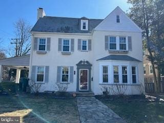 view of front of house with a carport, a chimney, and fence