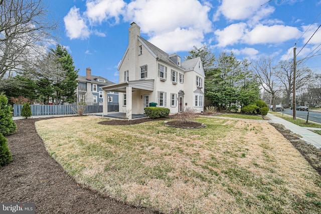 view of front of home with a front lawn, fence, and a chimney