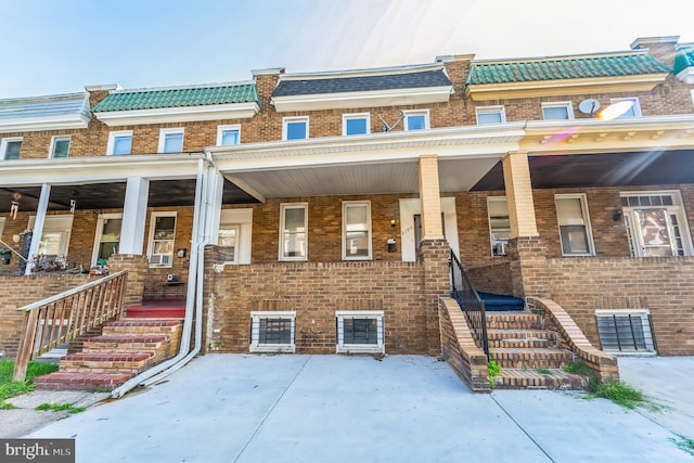 multi unit property featuring mansard roof, a porch, and brick siding