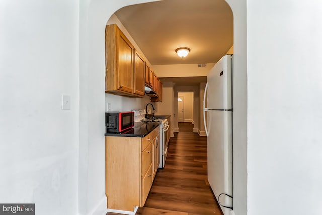 kitchen with arched walkways, dark countertops, visible vents, dark wood-type flooring, and white appliances