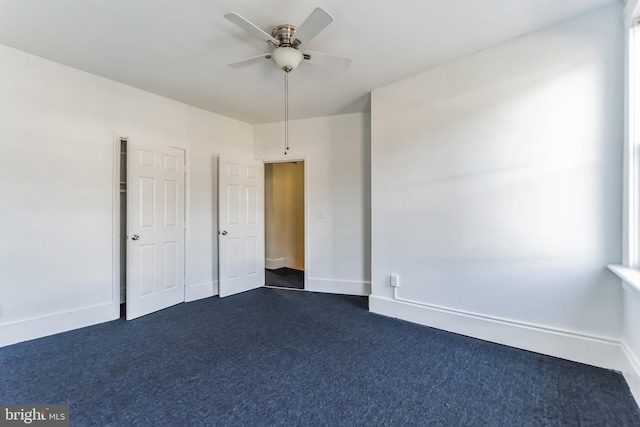 unfurnished bedroom featuring ceiling fan, dark carpet, and baseboards