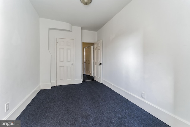 unfurnished bedroom featuring dark colored carpet and baseboards