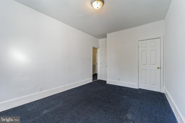 unfurnished bedroom with baseboards and dark colored carpet