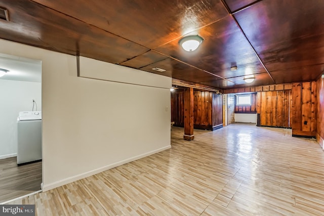 below grade area with washer / clothes dryer, wood ceiling, wooden walls, wood finished floors, and baseboards