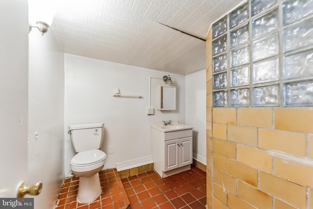 bathroom with tile patterned flooring, baseboards, vanity, and toilet