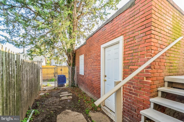 view of side of home with a gate, brick siding, and fence