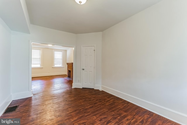 unfurnished room featuring dark wood-style flooring, visible vents, and baseboards