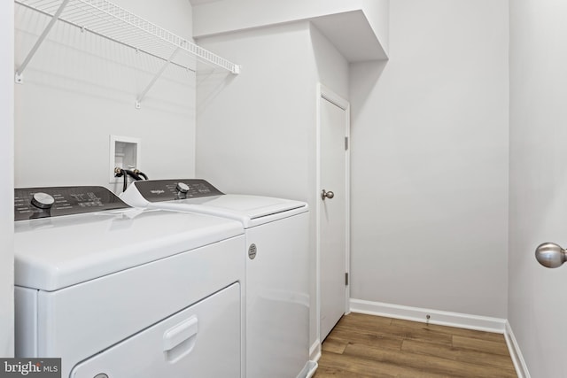 washroom with laundry area, baseboards, separate washer and dryer, and wood finished floors