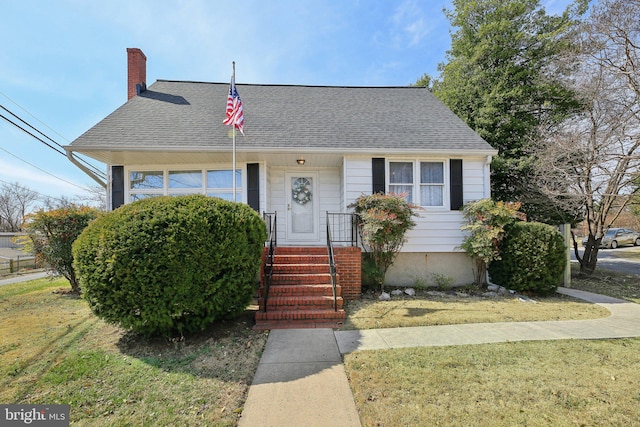 view of front of house featuring a front lawn, a chimney, and a shingled roof