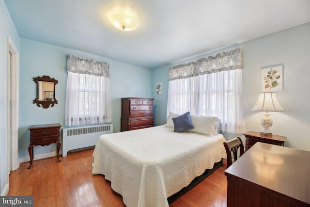 bedroom featuring radiator heating unit, baseboards, and wood finished floors