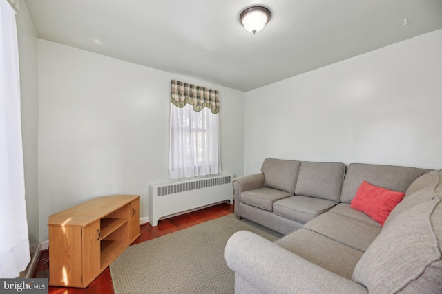 living room featuring baseboards, dark wood-style flooring, and radiator heating unit