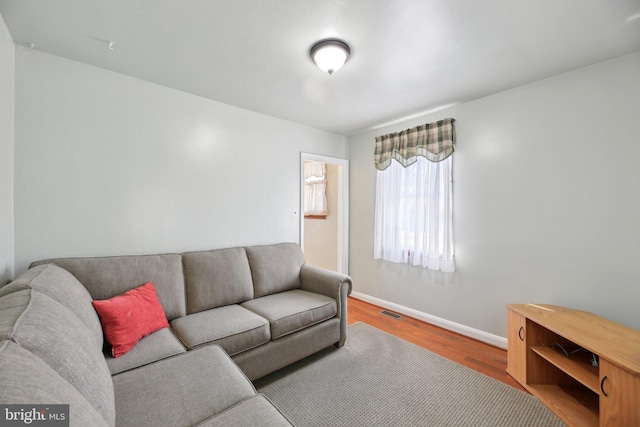 living room featuring visible vents, baseboards, and wood finished floors