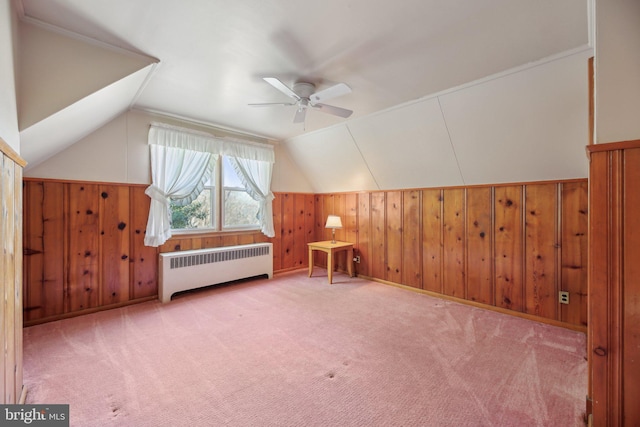 bonus room with a ceiling fan, carpet floors, radiator heating unit, vaulted ceiling, and wood walls