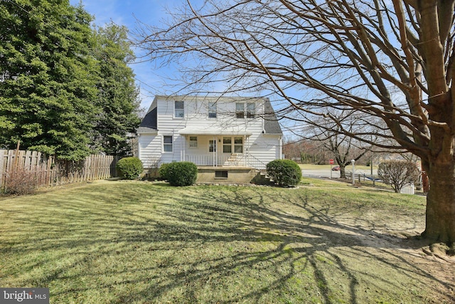 view of front of property with covered porch, a front lawn, and fence