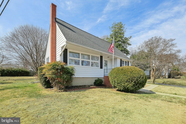 view of front facade featuring a front yard, roof with shingles, and a chimney