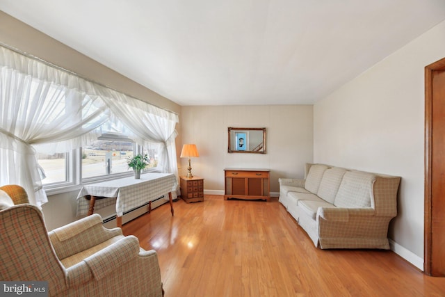 living area with light wood-style floors, baseboards, and baseboard heating