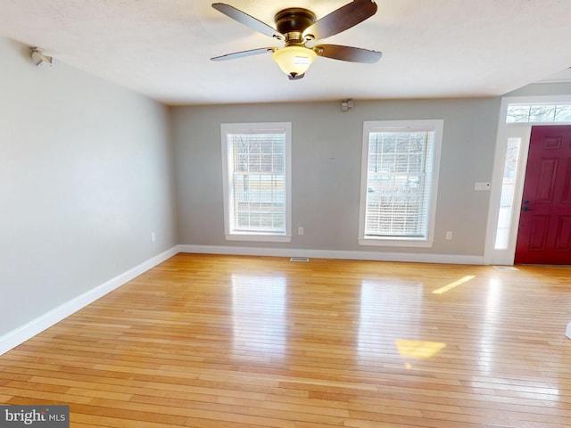 foyer entrance with a ceiling fan, baseboards, light wood-type flooring, and a wealth of natural light