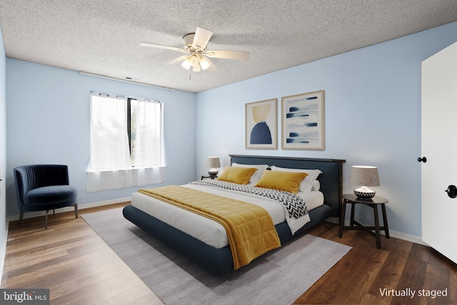 bedroom with ceiling fan, a textured ceiling, baseboards, and wood finished floors