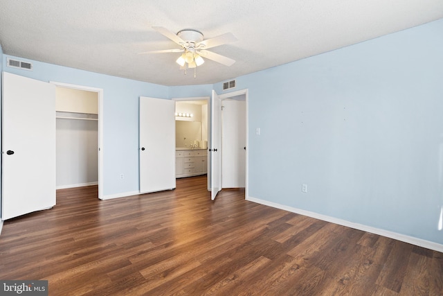 unfurnished bedroom with a closet, wood finished floors, visible vents, and baseboards