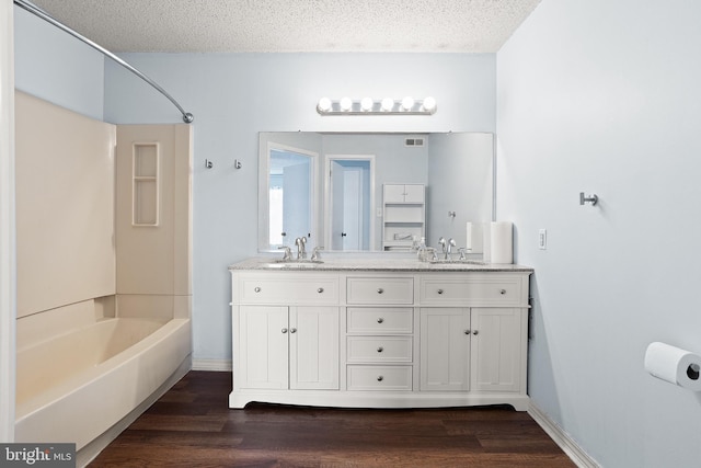 full bathroom featuring shower / bath combination, a textured ceiling, a sink, and wood finished floors