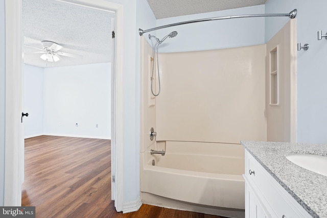 full bath with shower / bath combination, a ceiling fan, a textured ceiling, vanity, and wood finished floors