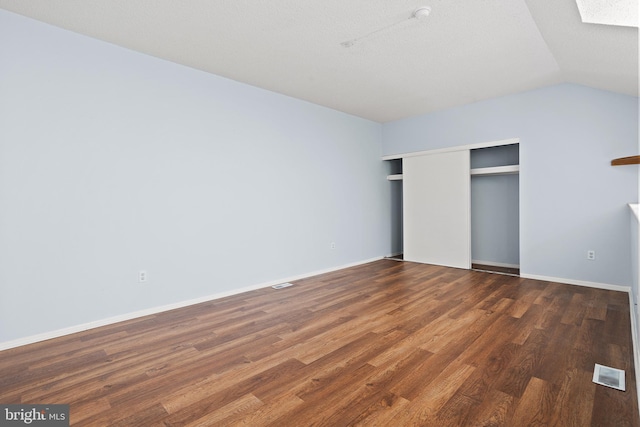 unfurnished bedroom featuring vaulted ceiling with skylight, wood finished floors, visible vents, baseboards, and a closet