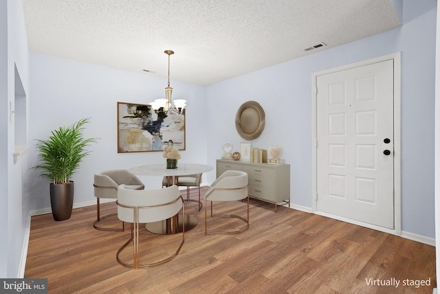 sitting room with an inviting chandelier, a textured ceiling, baseboards, and wood finished floors