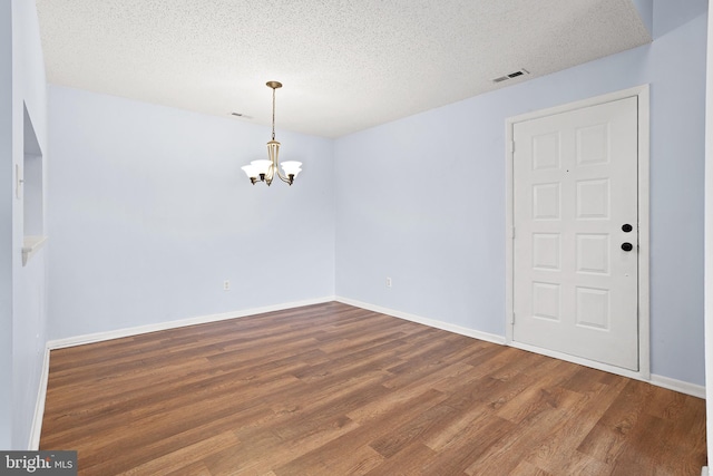 interior space with visible vents, baseboards, wood finished floors, an inviting chandelier, and a textured ceiling