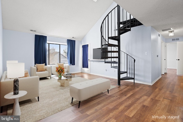 living area featuring a textured ceiling, wood finished floors, and visible vents