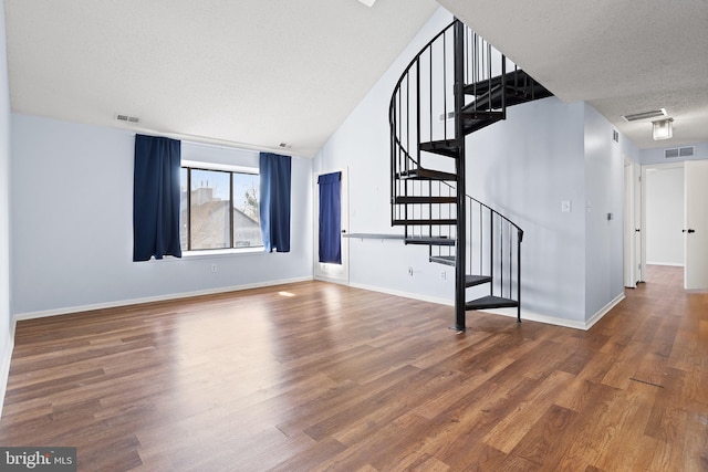 unfurnished living room with a textured ceiling, visible vents, and wood finished floors