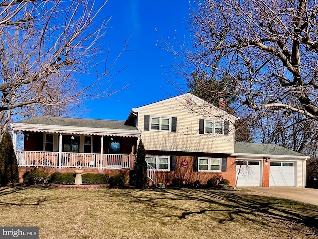 tri-level home with a garage, covered porch, concrete driveway, and a front yard